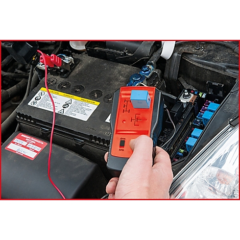 Nahaufnahme von einem Mann, der ein Relais-Testgerät an einem Auto verwendet. Ein rotes Kabel ist an der Autobatterie befestigt.